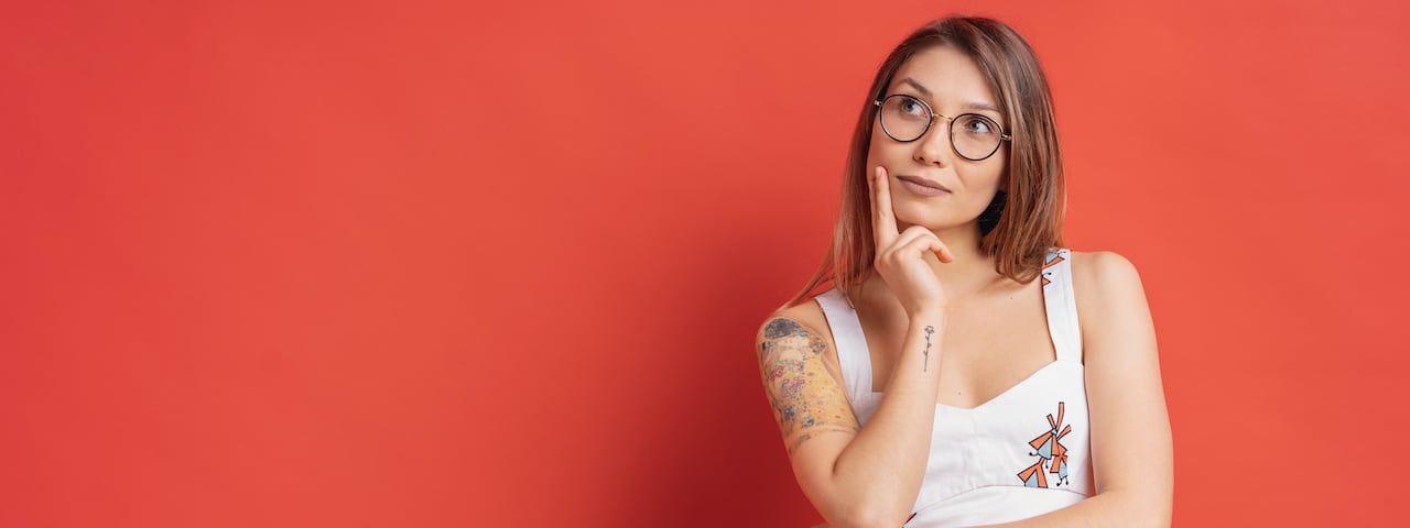 Caucasian woman with glasses thinking and imagination isolated on red background