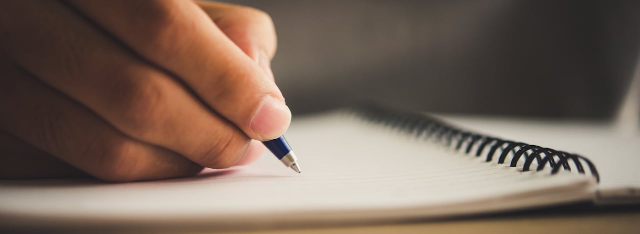 Man hand with pen writing on notebook.